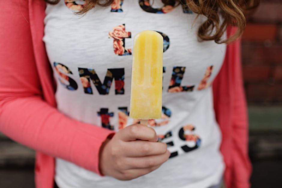 pexels-photo-540530-540530 Close-up of a child holding a bright yellow popsicle with a colorful shirt and jacket.